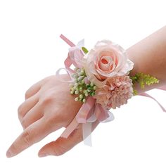 a woman's hand holding a pink flower wrist corsage