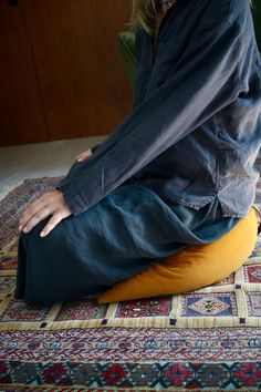 a woman sitting on top of a colorful rug