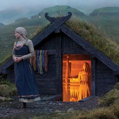 a woman standing in front of a small hut