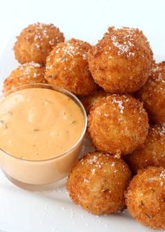 some fried food on a white plate with dipping sauce