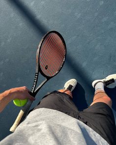 a man holding a tennis racquet and ball on top of a tennis court