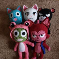 several knitted toys are arranged on the floor, including one with an angry cat face