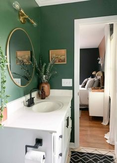 a bathroom with green walls and white counter top, plants in vases on the sink