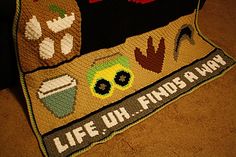 there is a knitted blanket that says life uh finds a way on the floor