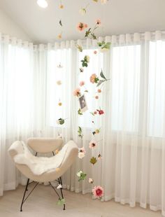 a white chair sitting in front of a window with flowers hanging from it's sides