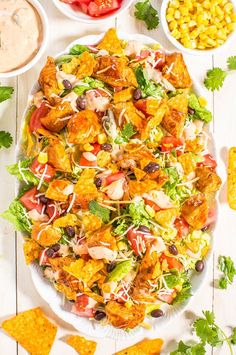 a salad with chicken, lettuce, tomatoes and black beans on a white plate