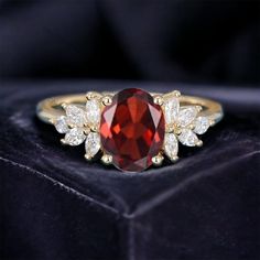 a ring with a large red stone surrounded by small white diamonds on a velvet box