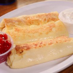 two quesadillas on a white plate with ketchup and sour cream