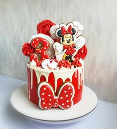 a birthday cake decorated with minnie mouse and number 3 on top is red and white