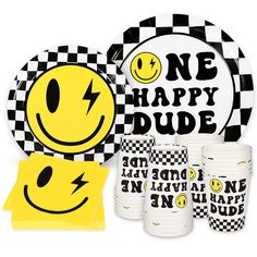 a table setting with plates, cups and napkins that have smiley faces on them