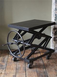 a black table with wheels on it sitting on a wooden floor