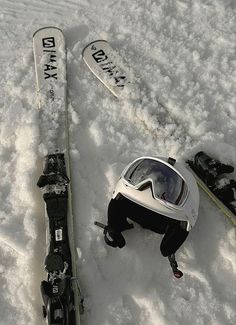 two snowboards and skis laying in the snow next to each other with goggles on them