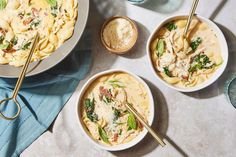 three bowls of pasta with spinach, chicken and parmesan cheese on the side