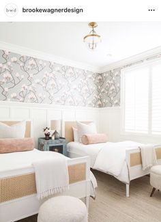 two beds in a bedroom with floral wallpaper on the walls and white bedding