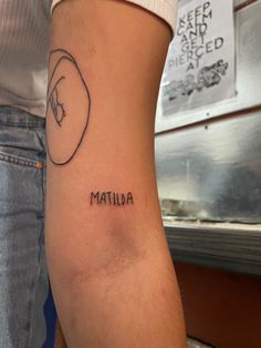 a woman with a tattoo on her arm that reads, mauna and has a face