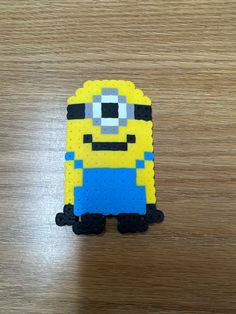 a yellow and blue lego minion sitting on top of a wooden table