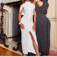 two women standing next to each other in front of a fire place wearing black and white dresses