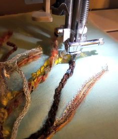 the sewing machine is working on many different colored thread and bead pieces that are being sewn together