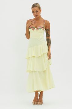 a woman in a yellow dress with tattoos on her arm and hand near her face