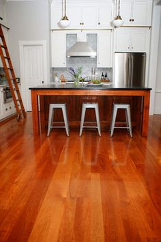 an open kitchen with wooden floors and white cabinets, along with ladders to the ceiling