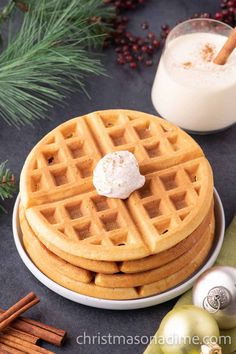 a stack of waffles sitting on top of a plate next to a glass of milk