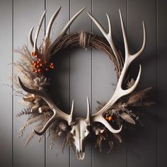 a deer skull wreath with antlers and berries hanging on the wall next to it