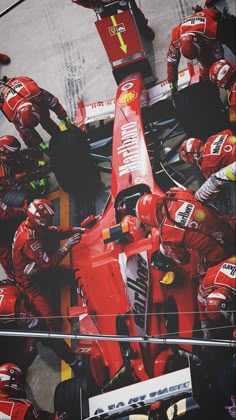 a group of men standing around a red race car