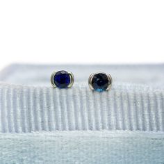 two pairs of blue stone earrings sitting on top of a white cloth