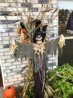 a scarecrow is standing in front of a brick wall with pumpkins and other decorations