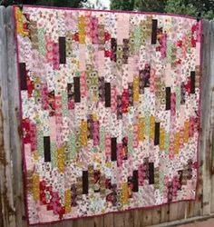 a quilt is hanging on a wooden fence