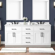 a bathroom with two sinks and mirrors on the wall next to rugs in front of them