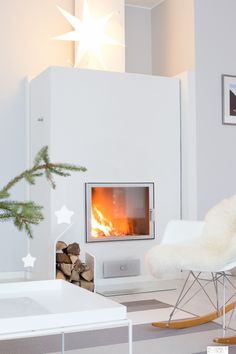 a white rocking chair sitting in front of a fire place next to a christmas tree