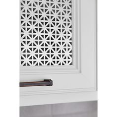 a close up of a door handle on a white cabinet with an intricate cut out design