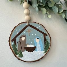 a christmas ornament with a nativity scene hanging from it's side