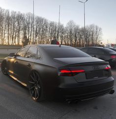 an audi car is parked in a parking lot with other cars behind it at sunset