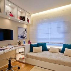 a white couch sitting in front of a flat screen tv mounted on a wall next to a desk