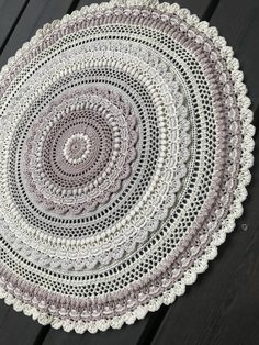 a crocheted doily is shown on a wooden table with black boards in the background