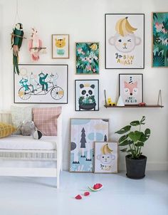 a living room filled with lots of pictures on the wall above a couch and potted plant