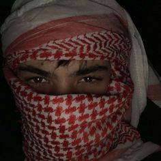 a man with a red and white scarf covering his face is looking at the camera