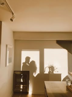 the shadow of two people standing next to each other in front of a kitchen counter