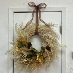 a white door with a wreath hanging on it's side and a brown ribbon