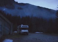 a white truck parked in front of a mountain with trees on it's side