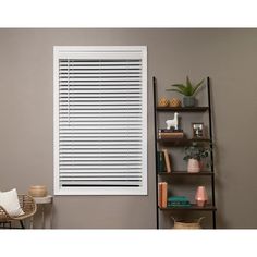 a living room filled with furniture and a window covered in white shutters next to a bookshelf