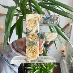 a person holding up a letter made out of flowers