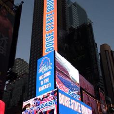 an illuminated building in the middle of a city with large billboards on it's sides