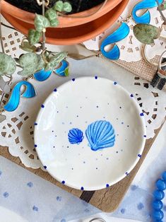 a white plate with blue designs on it next to a potted plant and scissors