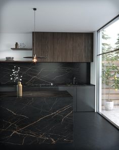 a kitchen with black marble counter tops and wooden cabinetry next to a large window