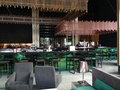 the interior of a restaurant with green and gray chairs, bar stools, and tables