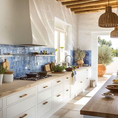 a kitchen with blue tiles on the wall and counter tops, along with potted plants