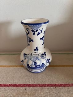 a small blue and white vase sitting on top of a tablecloth covered floor next to a wall